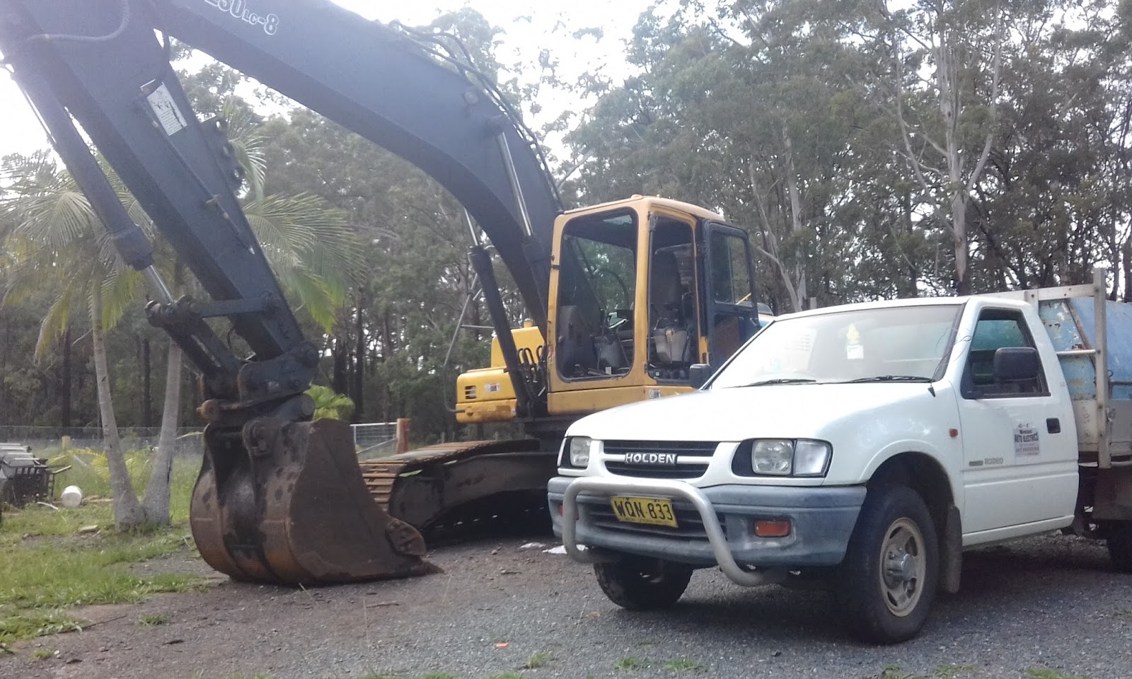 Wireman work ute parked beside an excavator on a rural job
