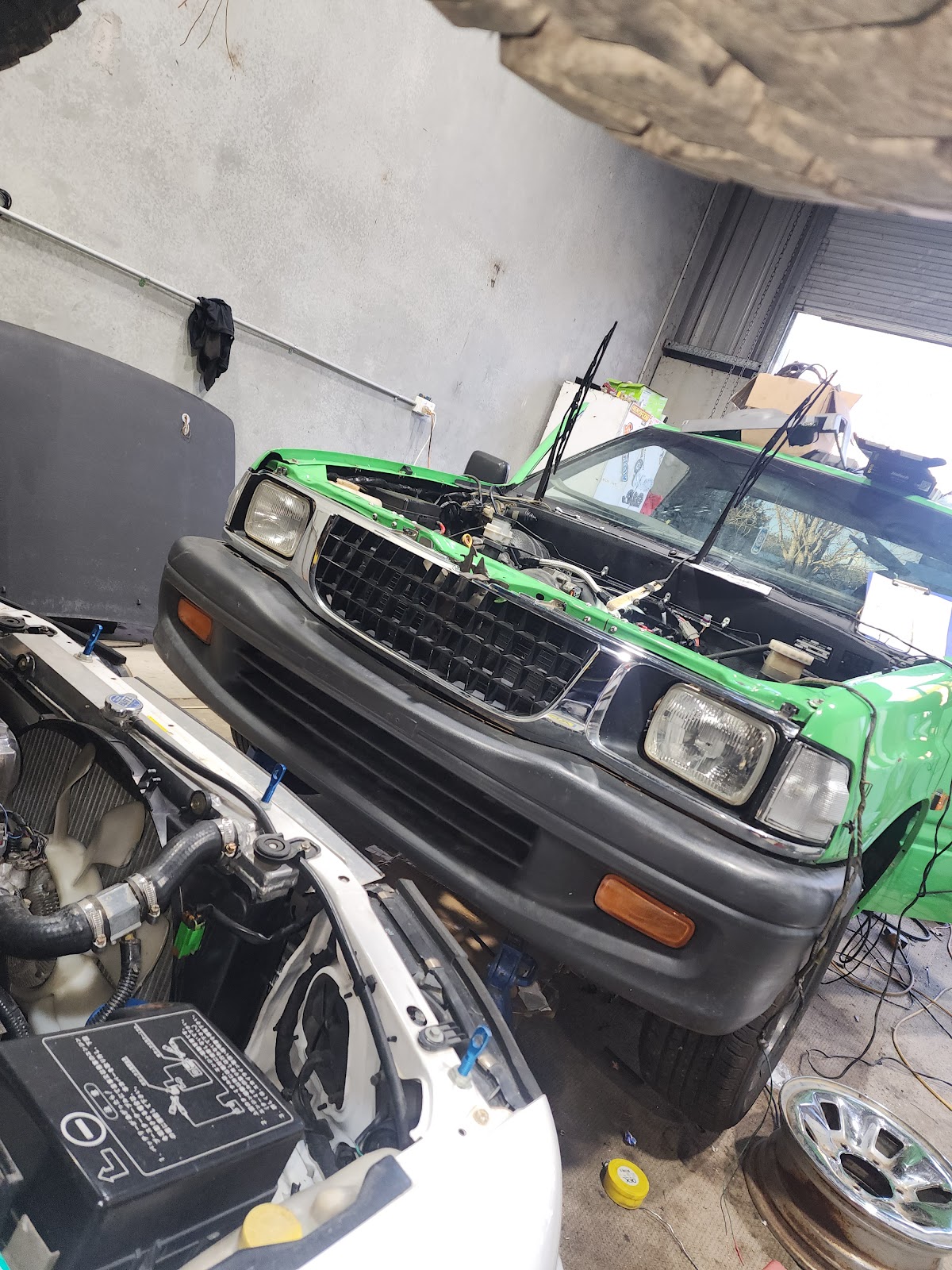 Green ute and white car side by side, bonnets up
