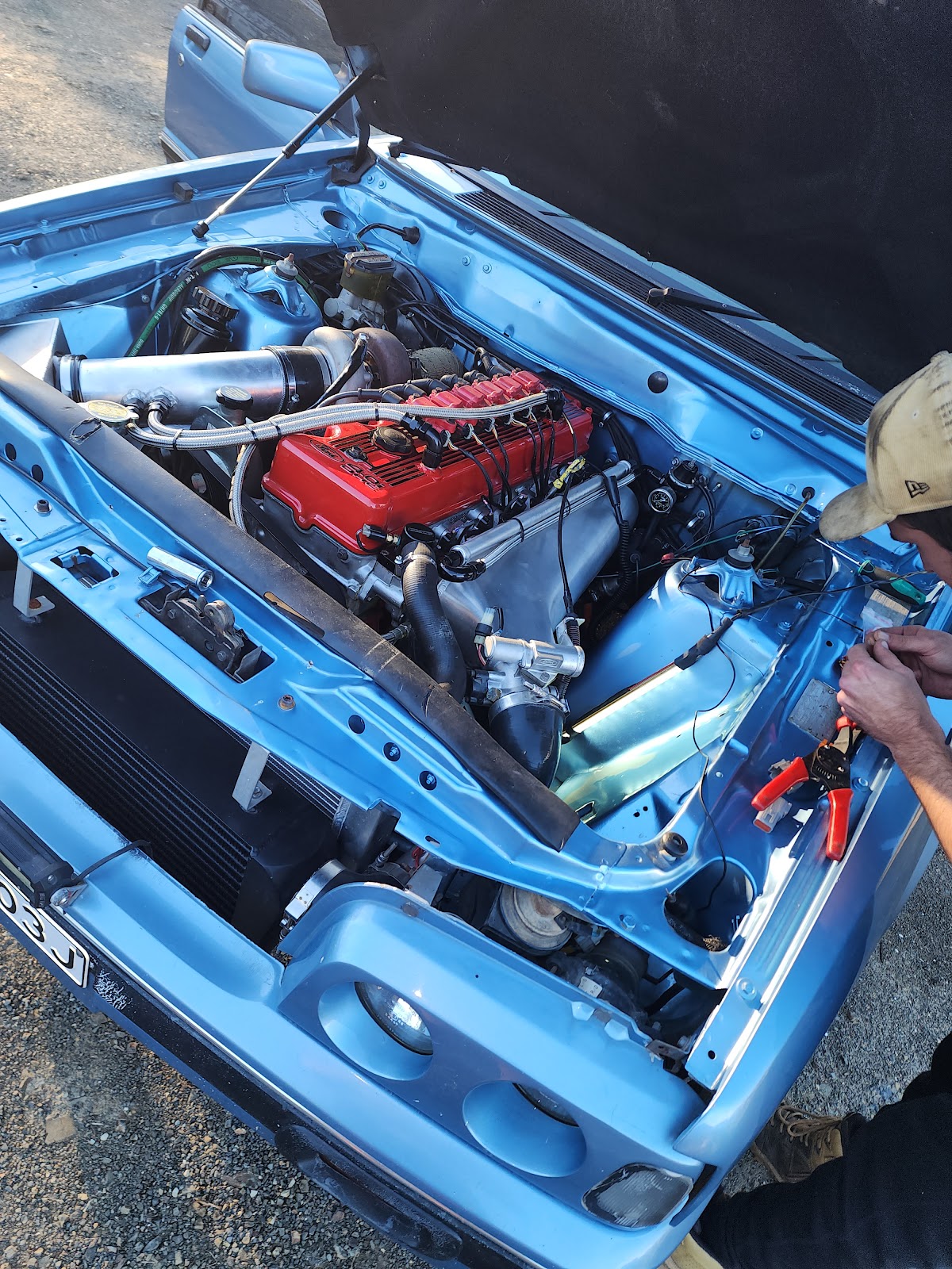 Turbo engine bay with a red rocker cover being wired up