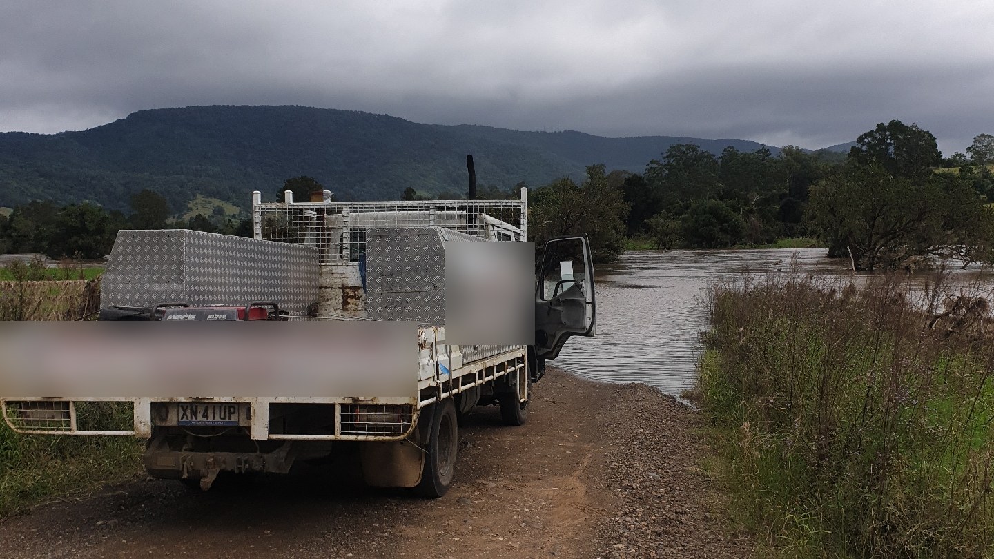 The Wireman Auto Electrics work ute parked by a flooded river under the hills